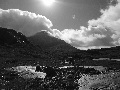 (34) The next three photographs features Maol Chean-dearg: the gaelic epithets "bald" and "red" are certainly true of much this bold-shaped hill. Here it is seen from the stepping stones on the Annat to Loch an Eòin path, with a thin layer of sunlit hill-cloud.  It's in black and white - partly because this view was a huge contrast of light and dark - not far off monochrome. We hope that conversion of this and photo (36) to black-and-white adds another element to the show: it also helped hide the photographer's problem of flare!