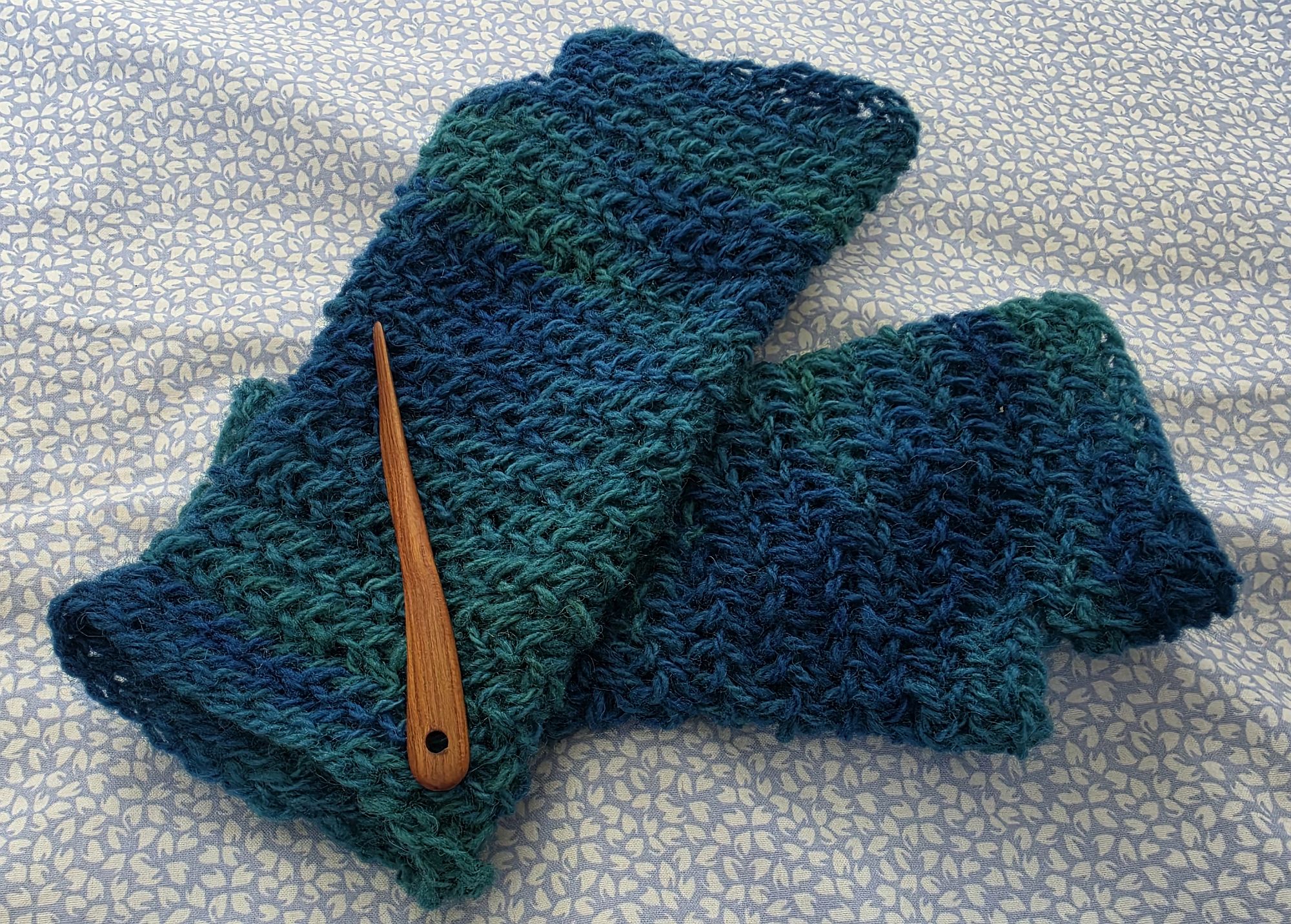 Finished blue-green wrist warmers with the nalbinding needle I used to make them. Finished blue-green wrist warmers with the nalbinding needle I used to make them.